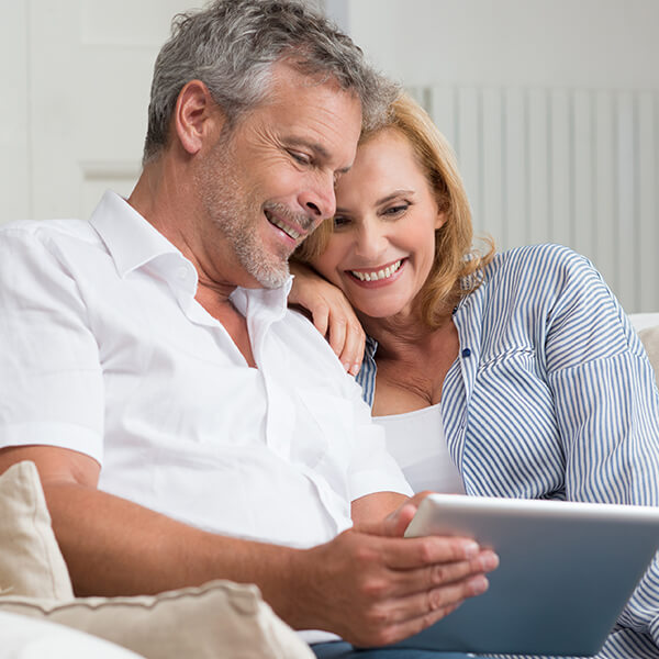 A mature couple looking at their tablet on the sofa