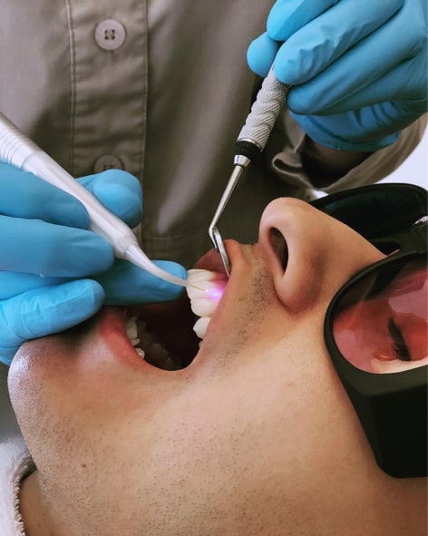 The doctor works with a laser in the oral cavity of the patient's mouth.