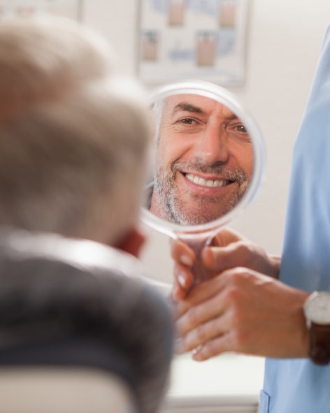 Adult patient smiling while looking at the mirror.